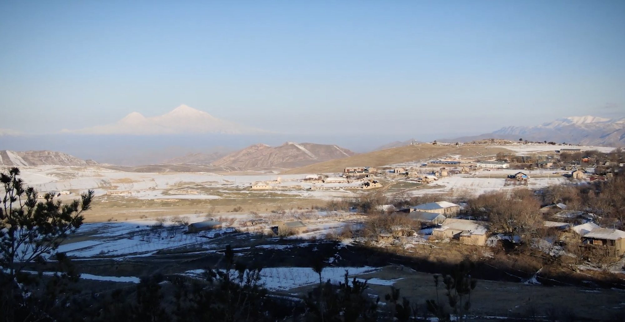 Snow on the hills above a border village, Mount Ararat on the horizon