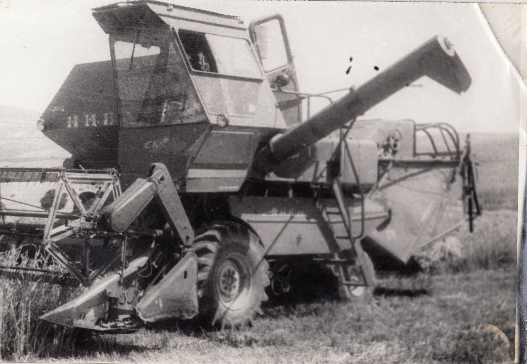 A combine harvester in a field, in an old black and white print