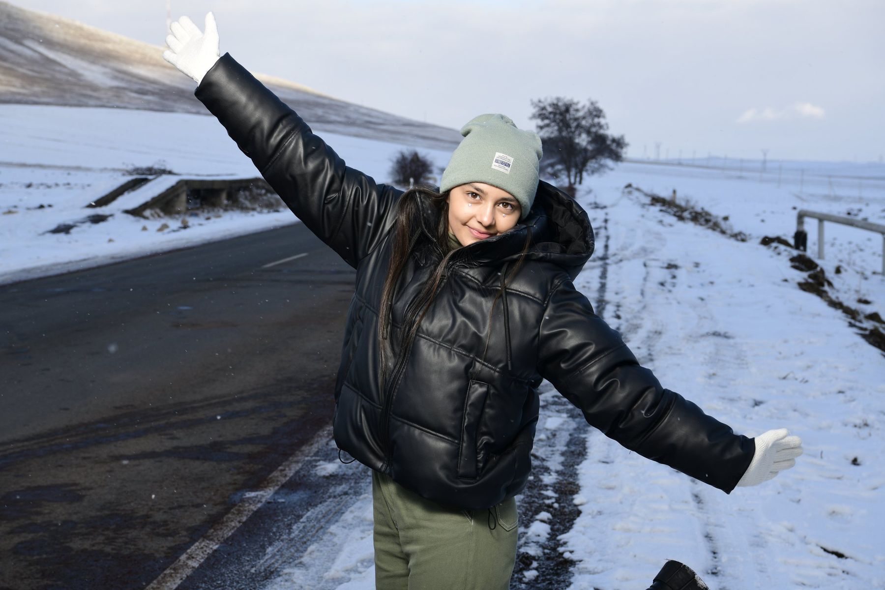 A girl throws her arms open on a snowy road