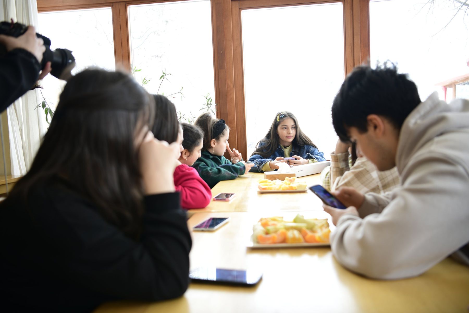 Teenagers around a long breakfast table by a snowy window