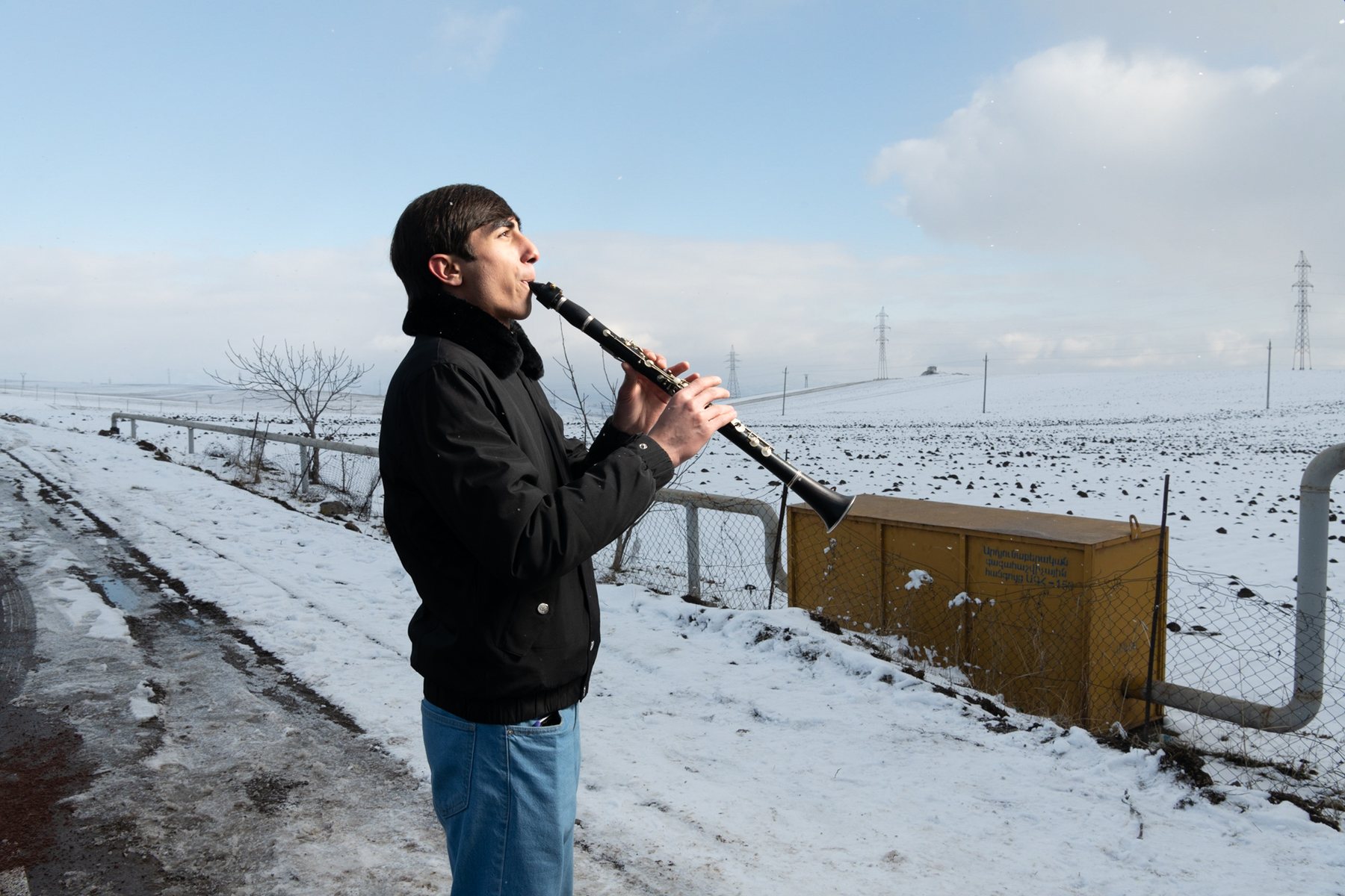 A boy plays clarinet against a snowy plain