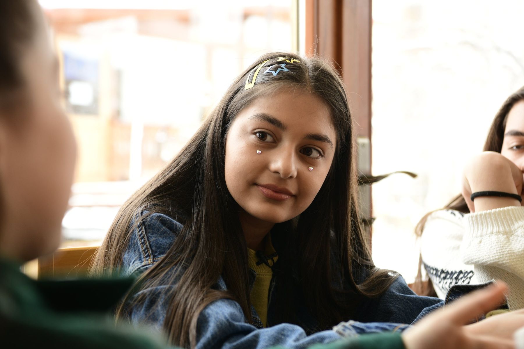 A girl at the table looks across at a friend