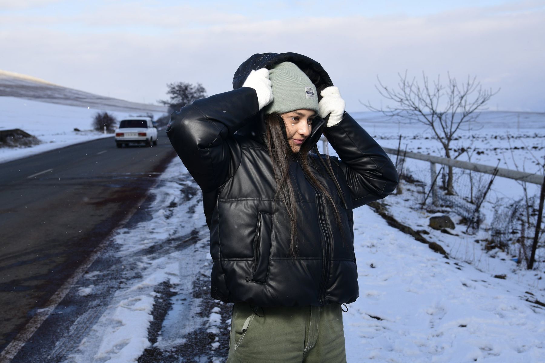 A girl jumps in the air on a snowy roadside