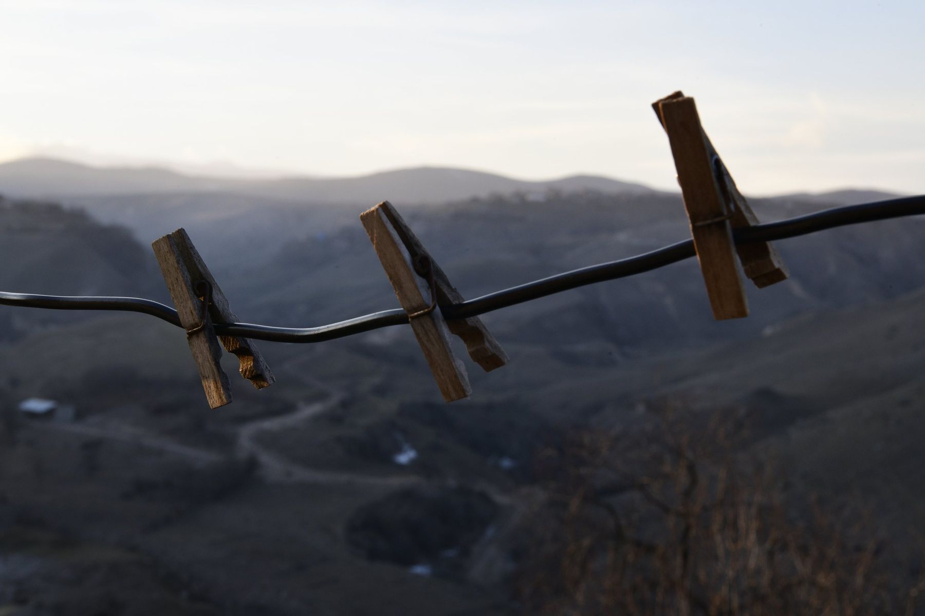 Clothes pegs on a wire, with blue mountains beyond