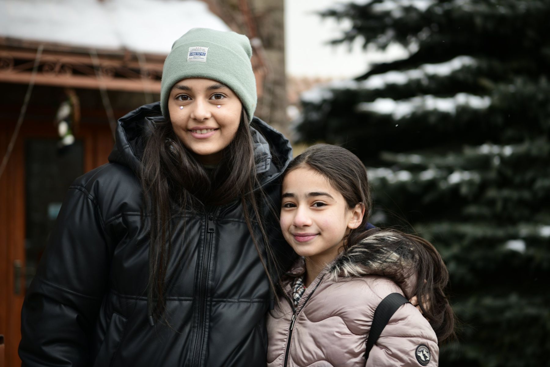 Two girls in winter coats smile into the camera