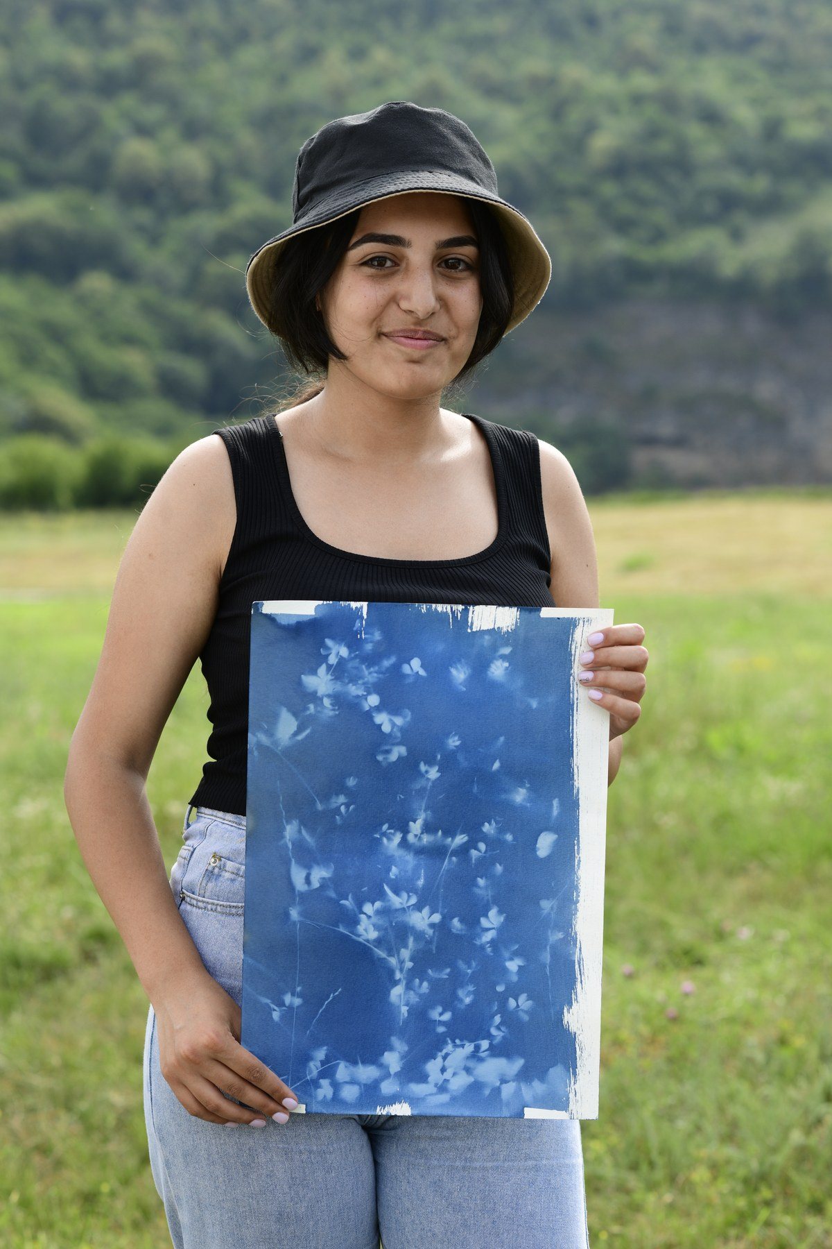 A girl in a black hat holds a blue print covered in leaf shapes
