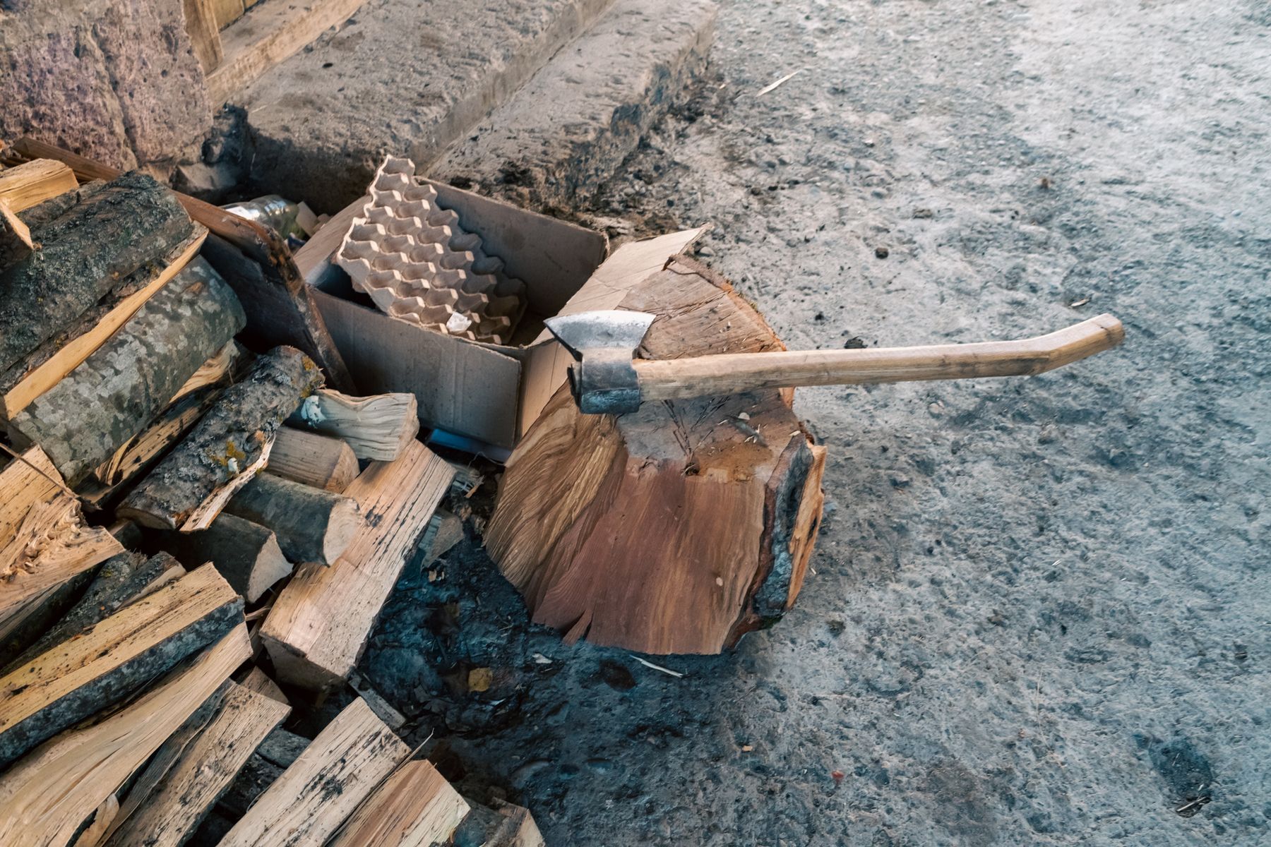 An axe rests on a chopping block among split logs
