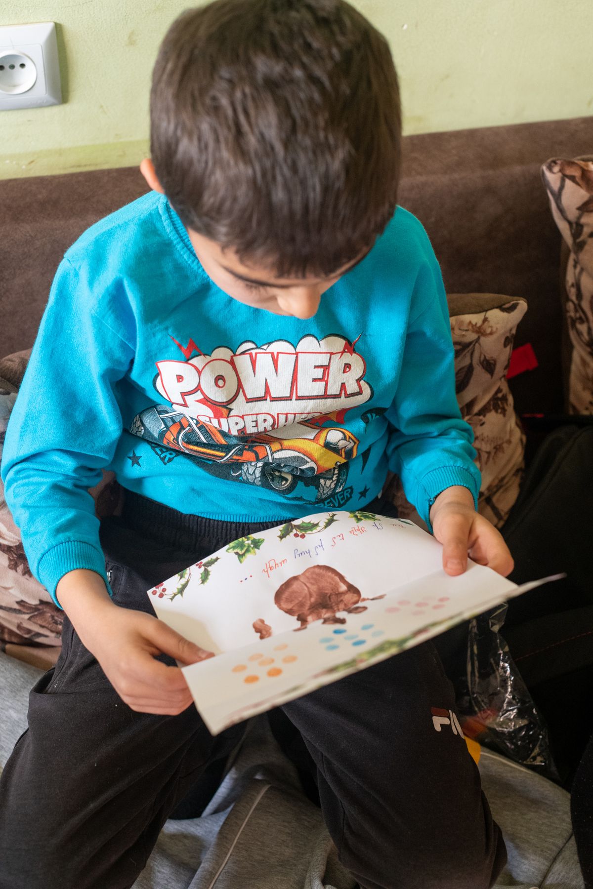 A boy in a POWER jumper looks at a drawing