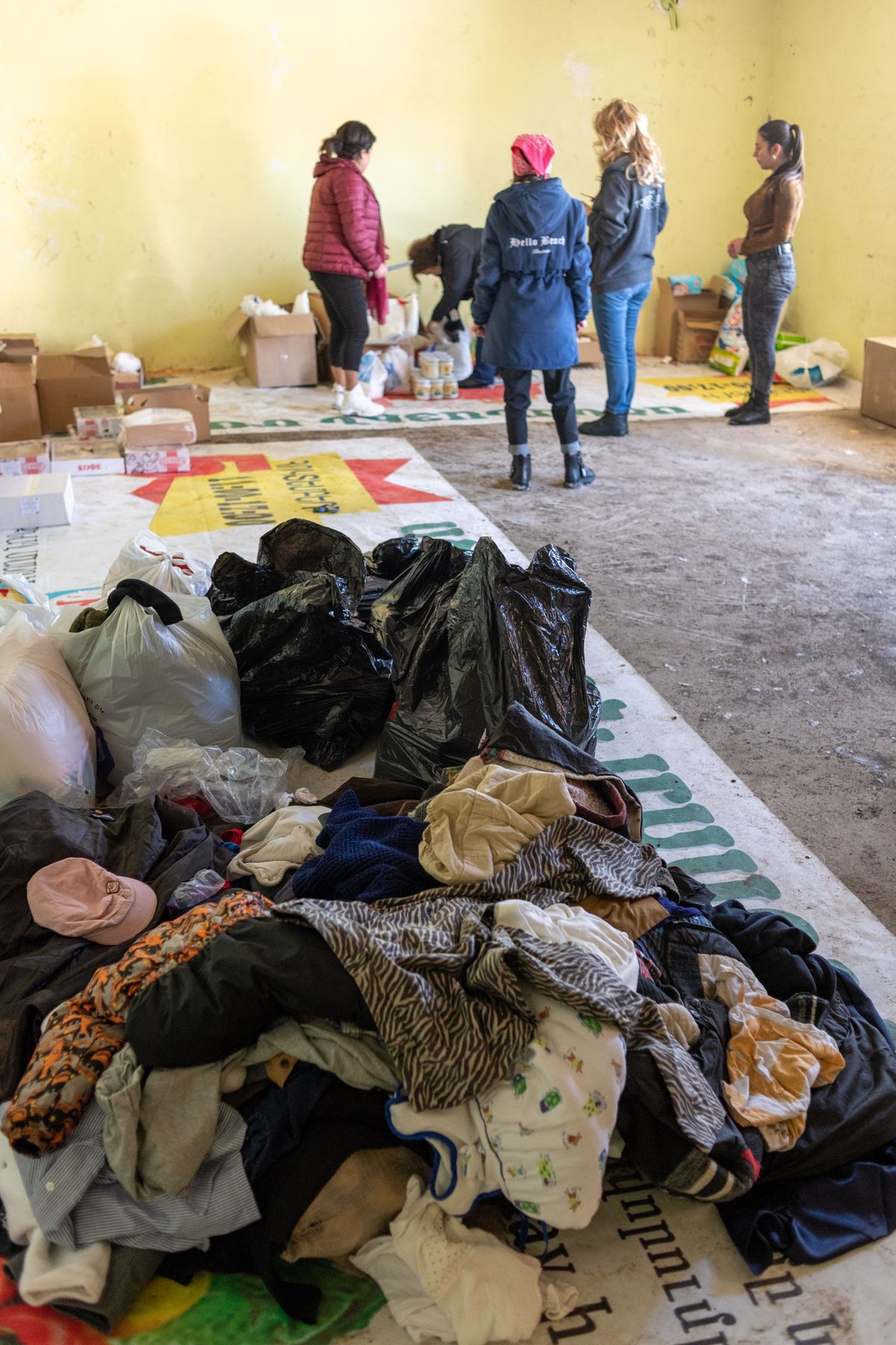 Volunteers sort piles of donated clothes on a hall floor