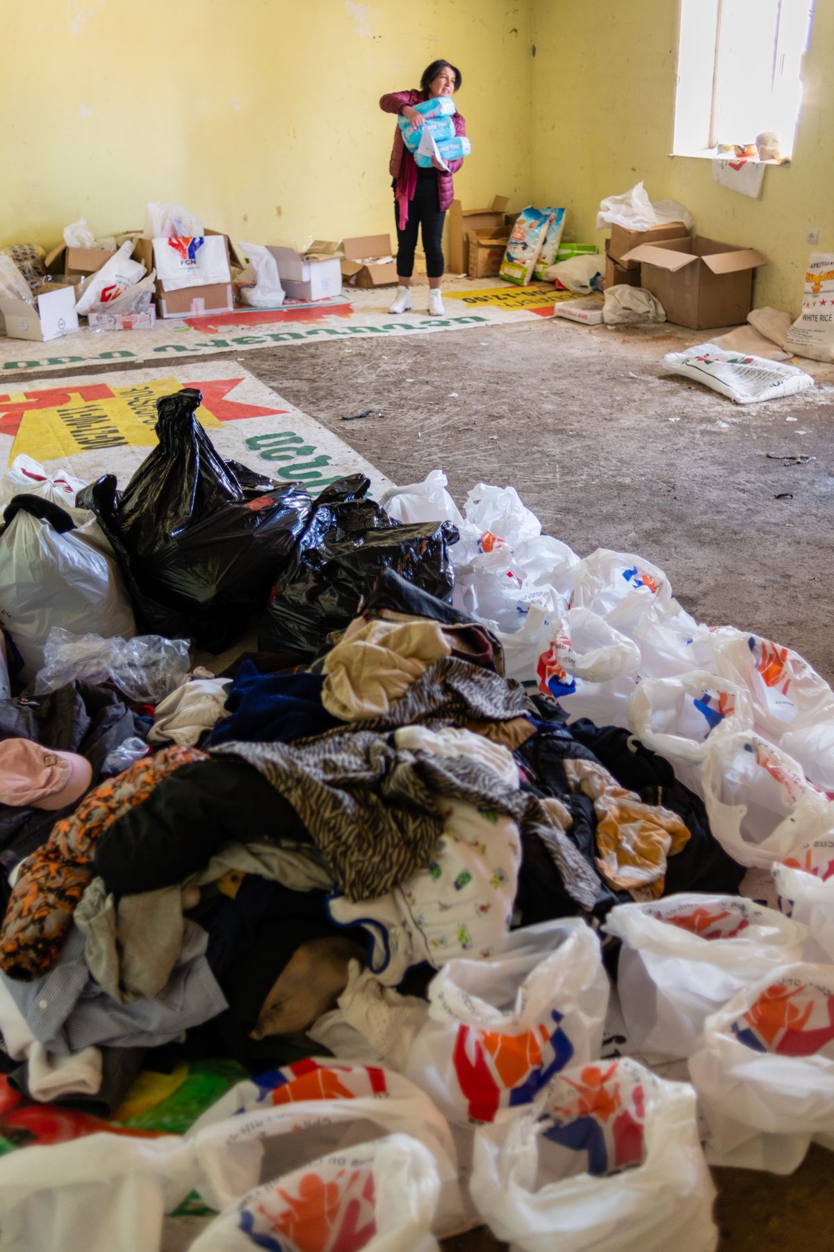 A hall floor covered with bags of donated food and clothes