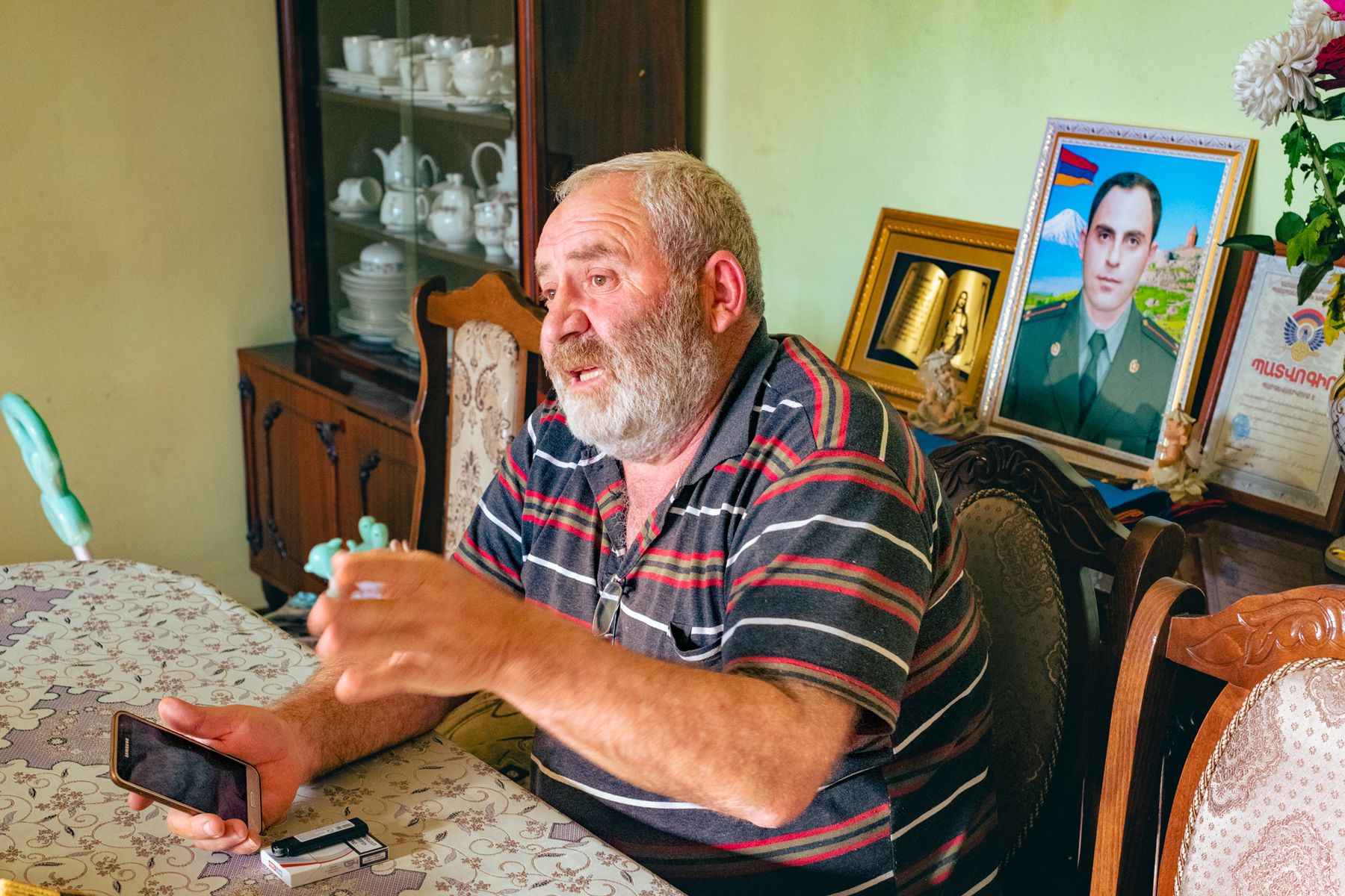 A man at a table beneath framed portraits of a young soldier