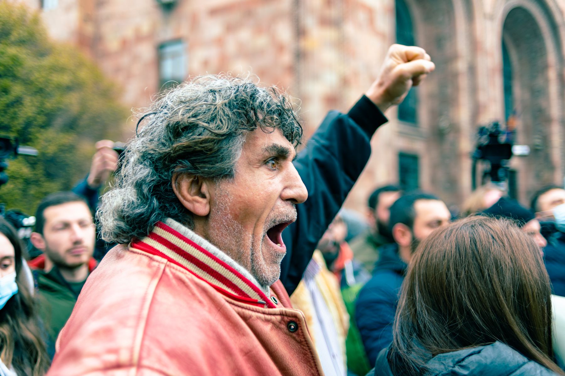 A grey-haired man shouts with his fist raised