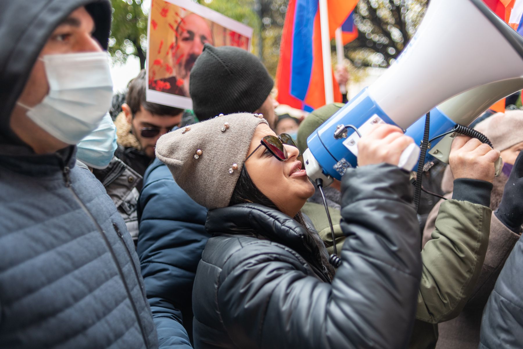 A masked woman shouts through a megaphone in a crowd