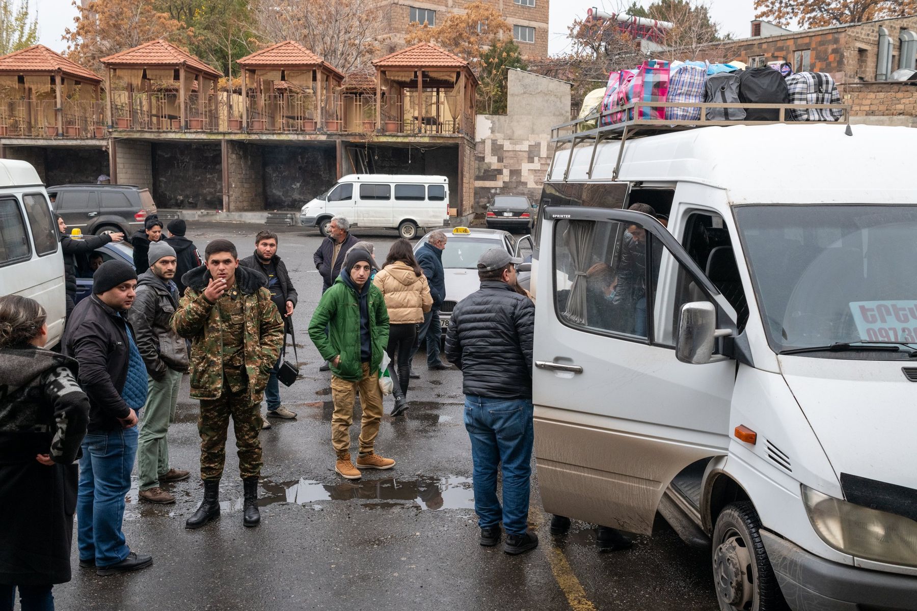 Soldiers and families gather around white minibuses in a car park