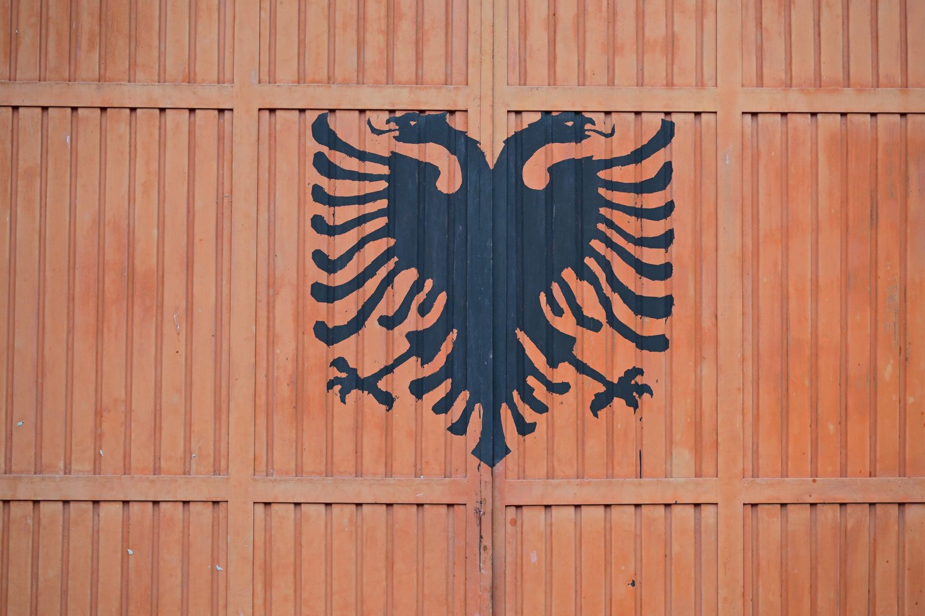 A double-headed eagle painted on an orange garage door