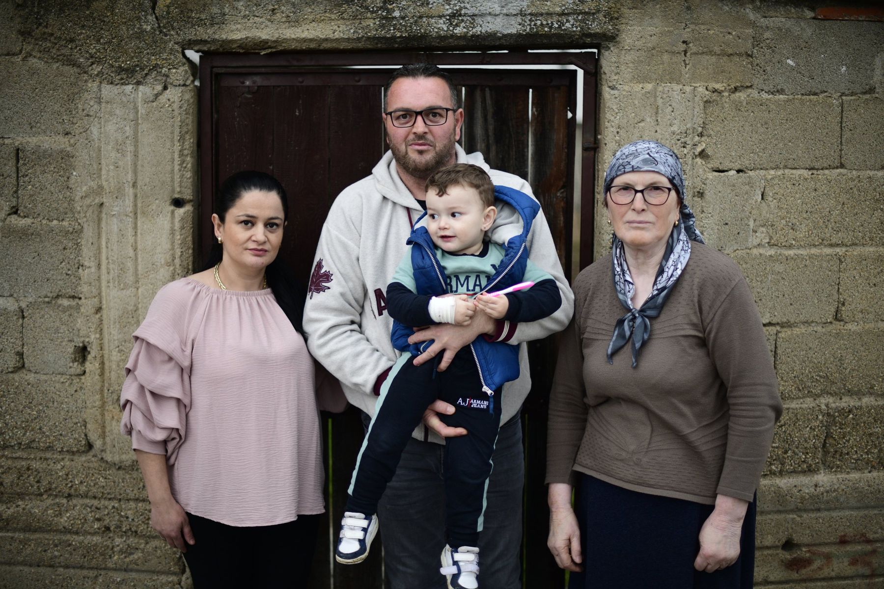 Three adults and a small child stand before an old wooden door