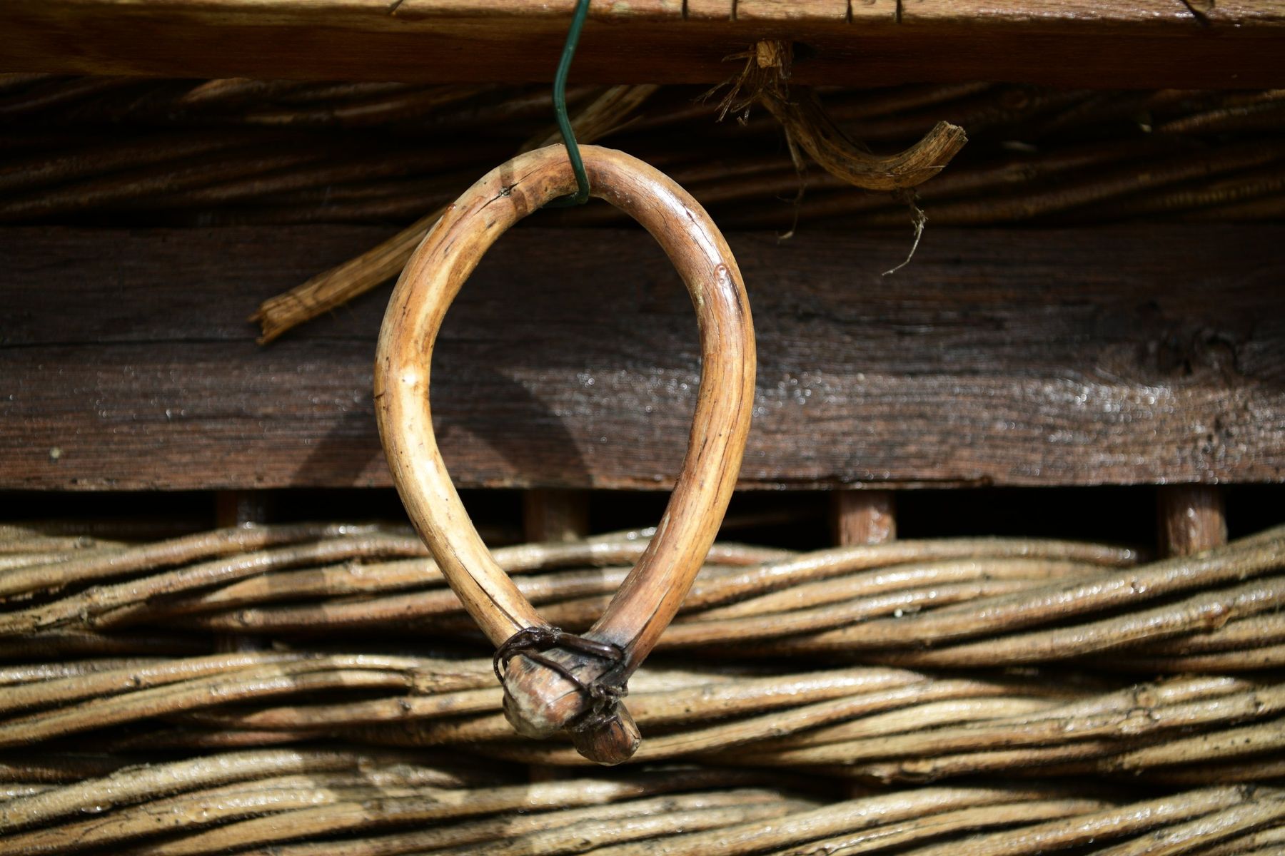 A wooden ox yoke hanging on a wall of woven branches
