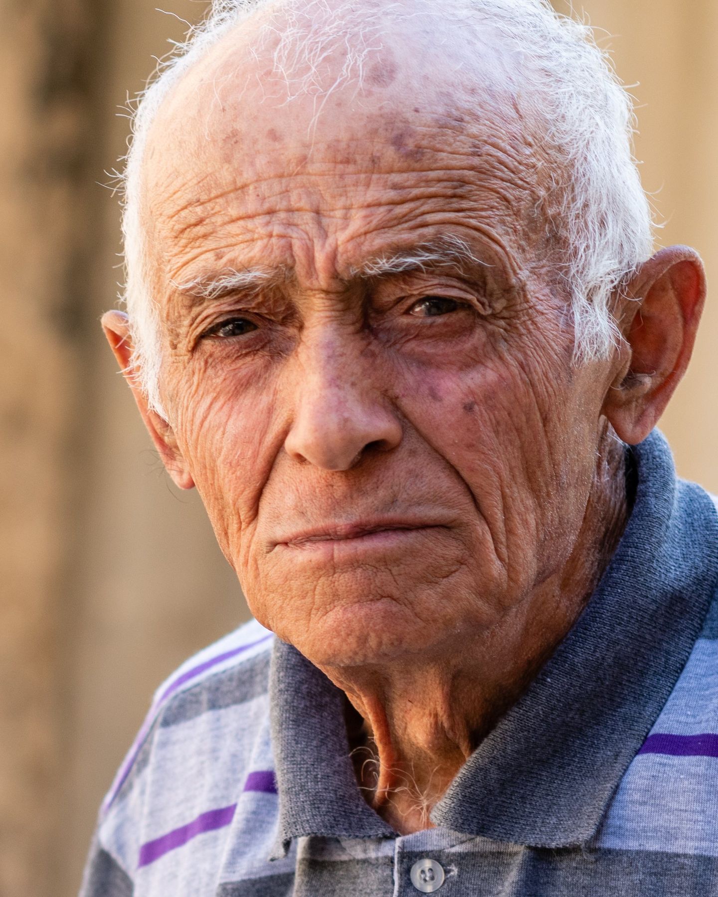 Portrait of an elderly man against a white wall