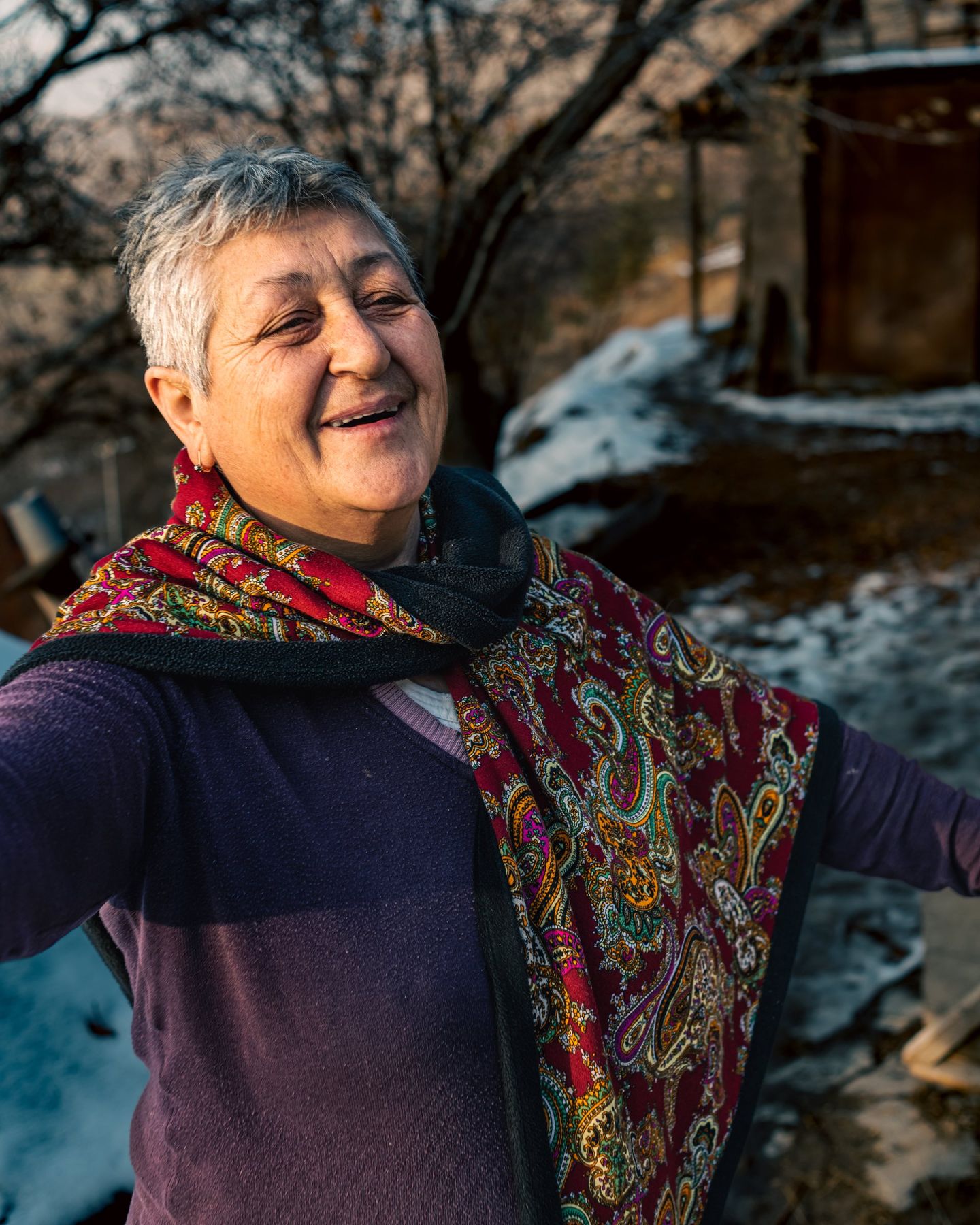 A woman in a patterned scarf smiles outdoors in winter