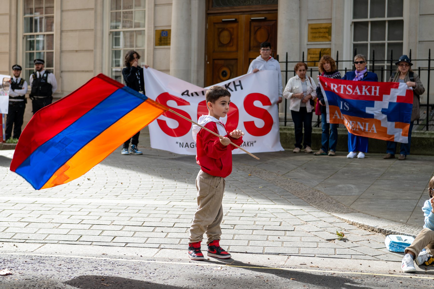 A small boy waves a large Armenian flag in the street