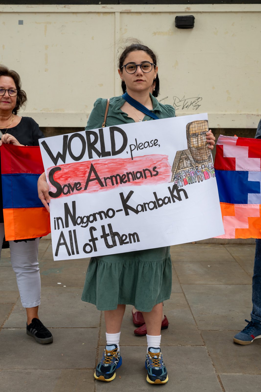 A woman holds a hand-drawn sign asking the world to save the Armenians of Nagorno-Karabakh