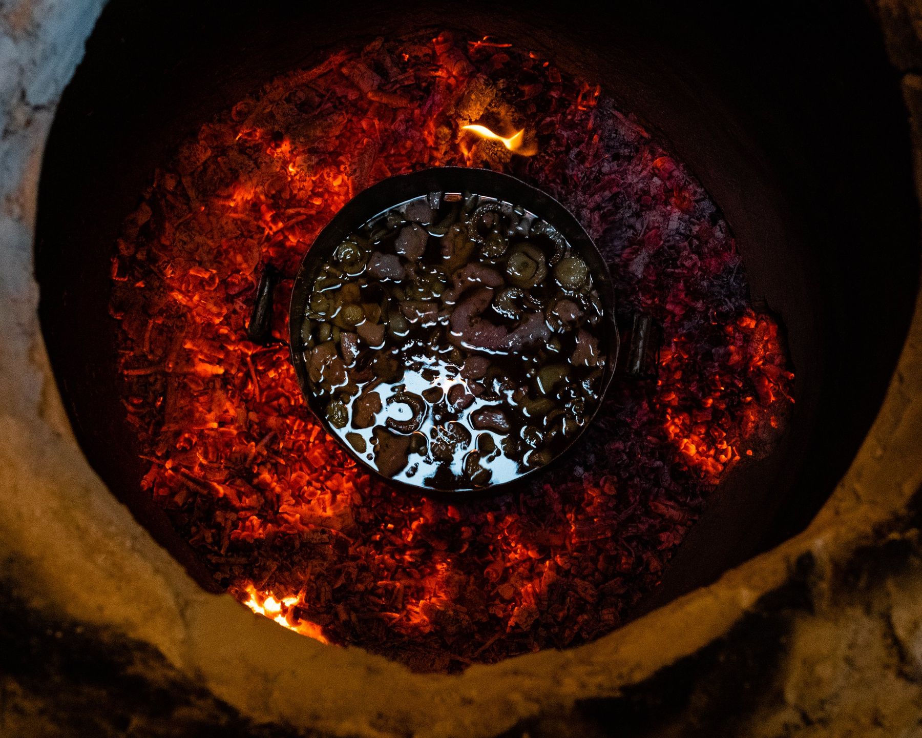 A pot set into the glowing embers of a tonir oven