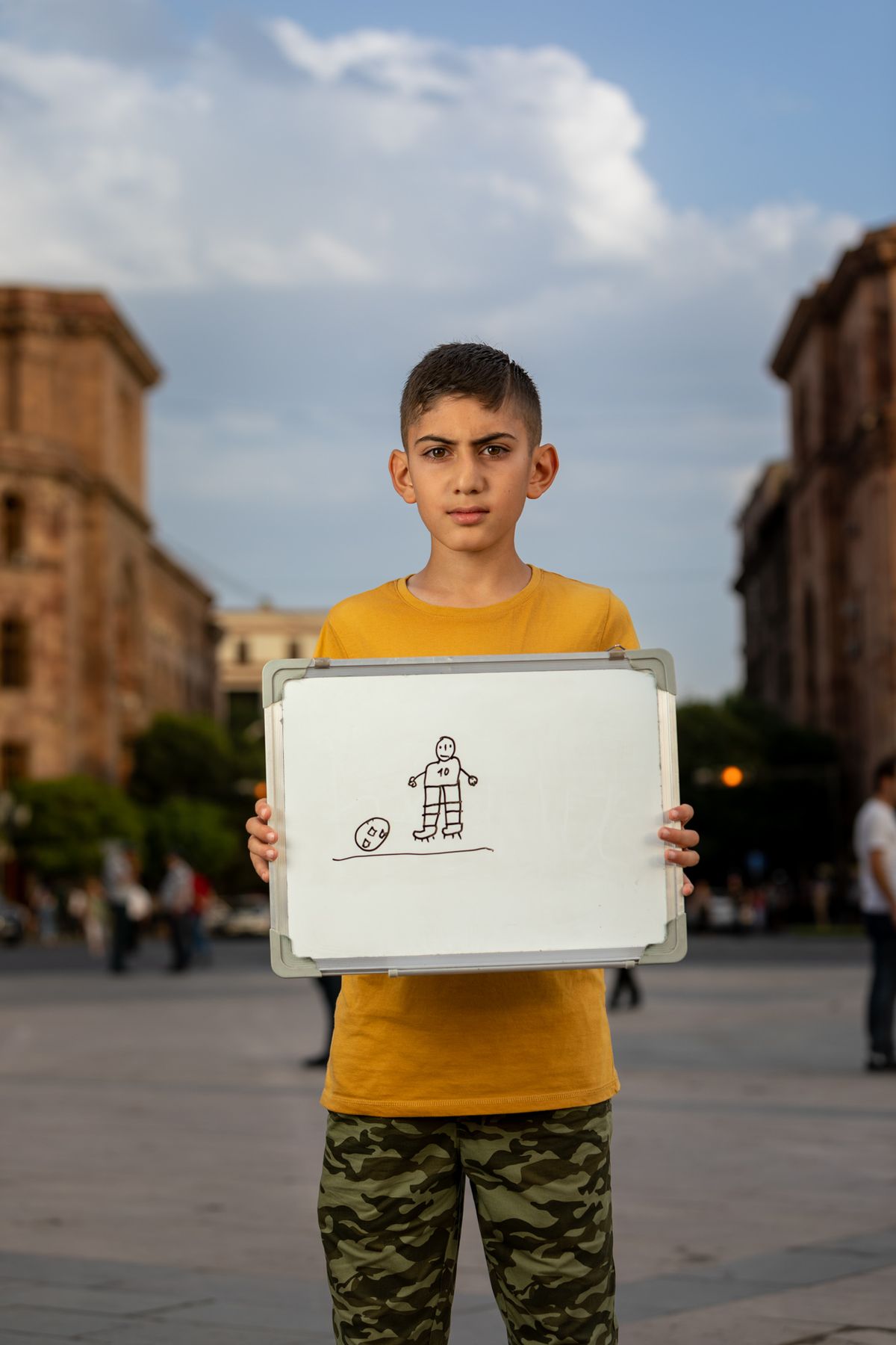 A boy holds a whiteboard with a drawing in Republic Square