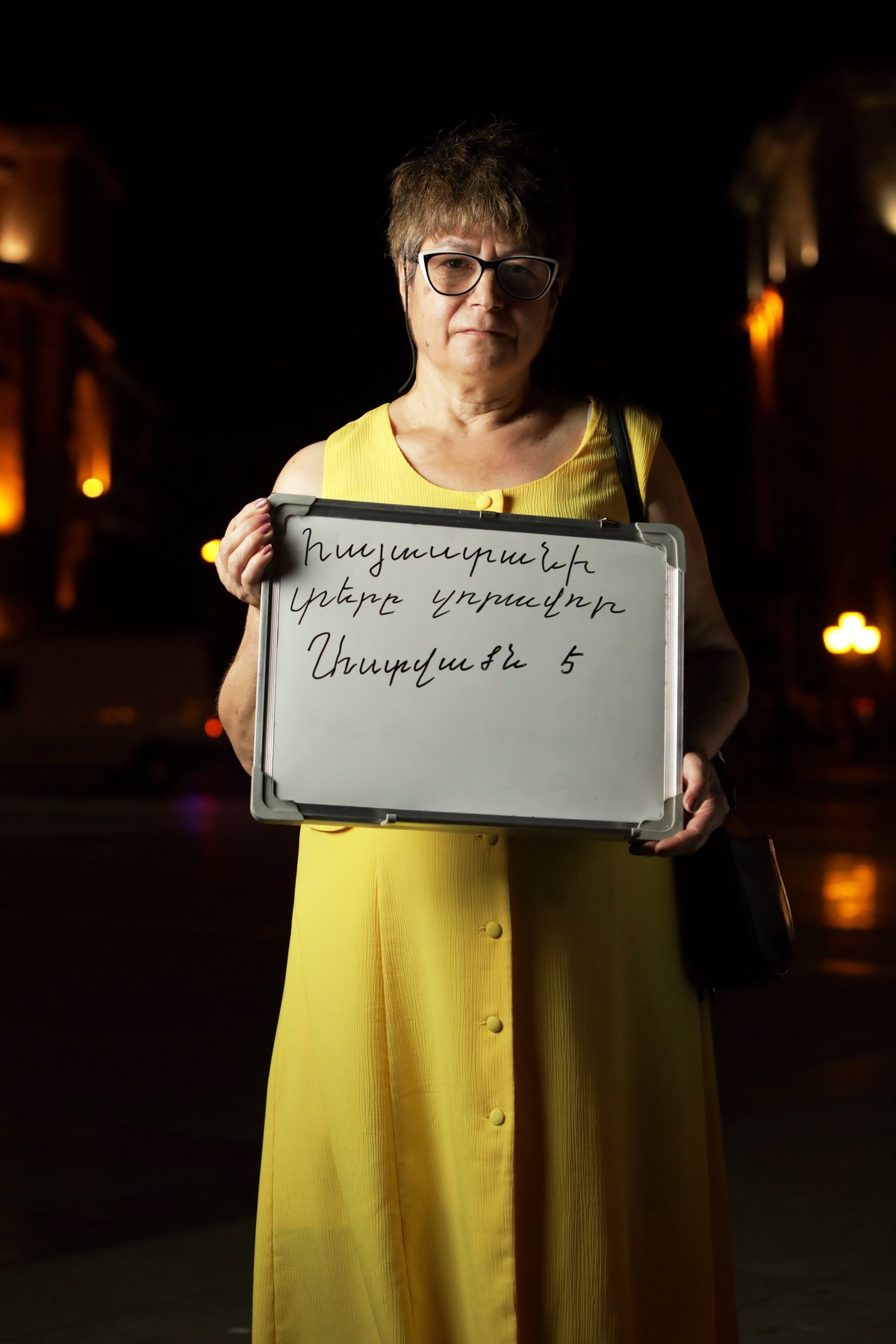 The same woman holds her handwritten whiteboard