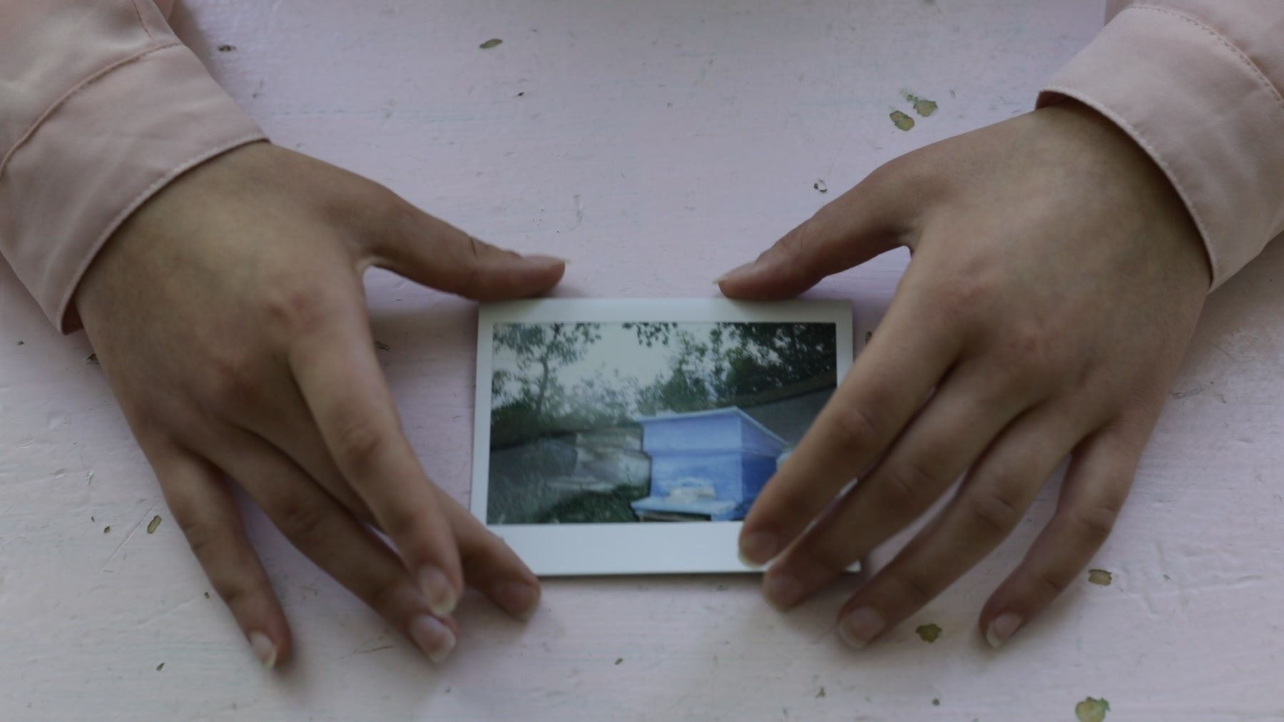 Two hands frame an instant print of a blue door