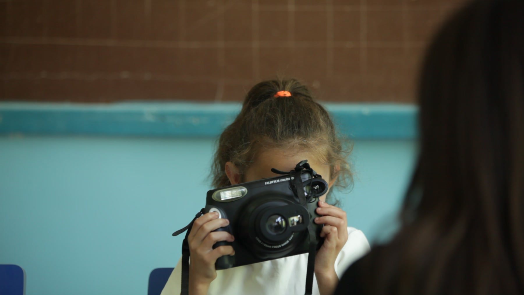 The youngest girl holds the Instax camera up to her face