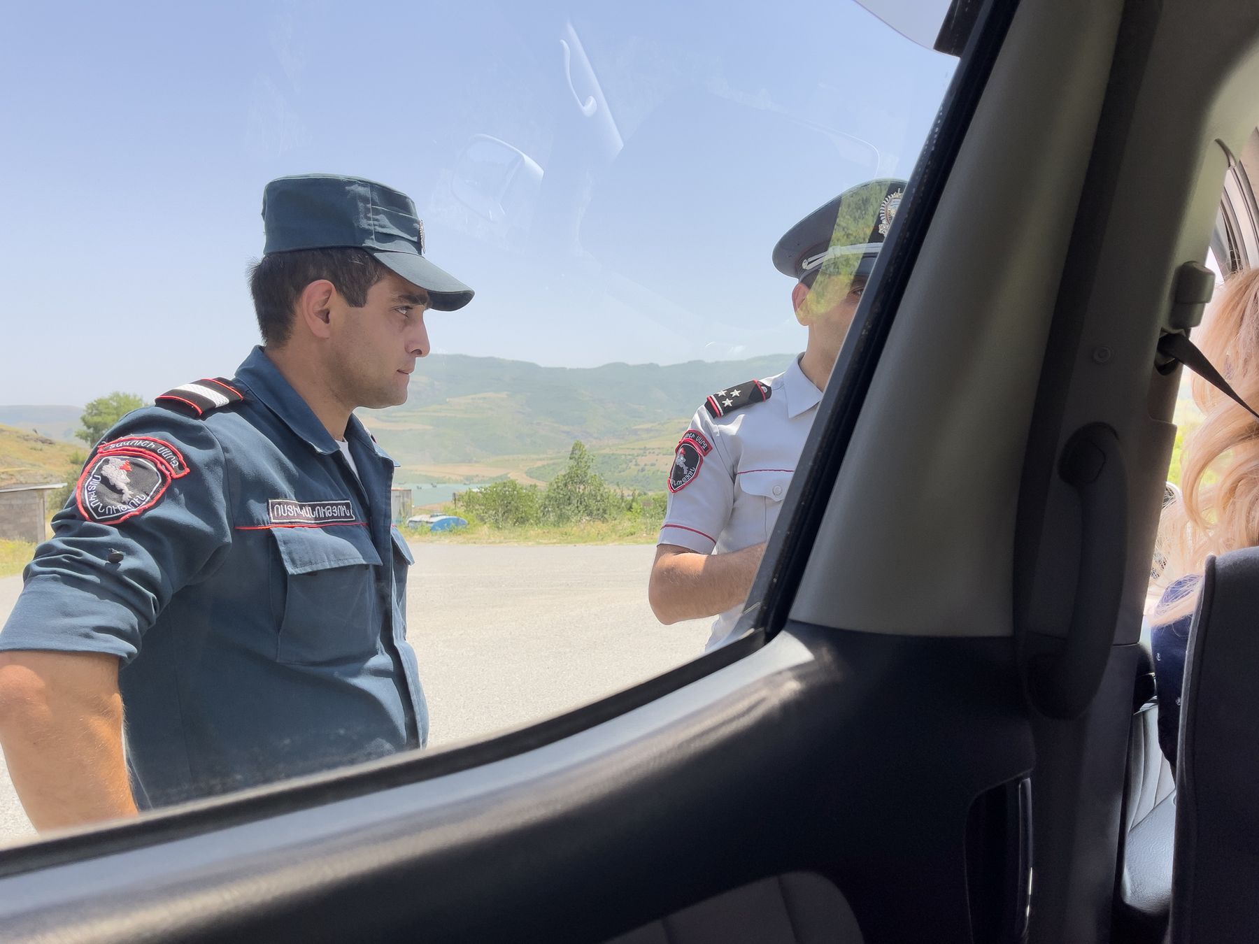 A police officer at a car window on a hill road