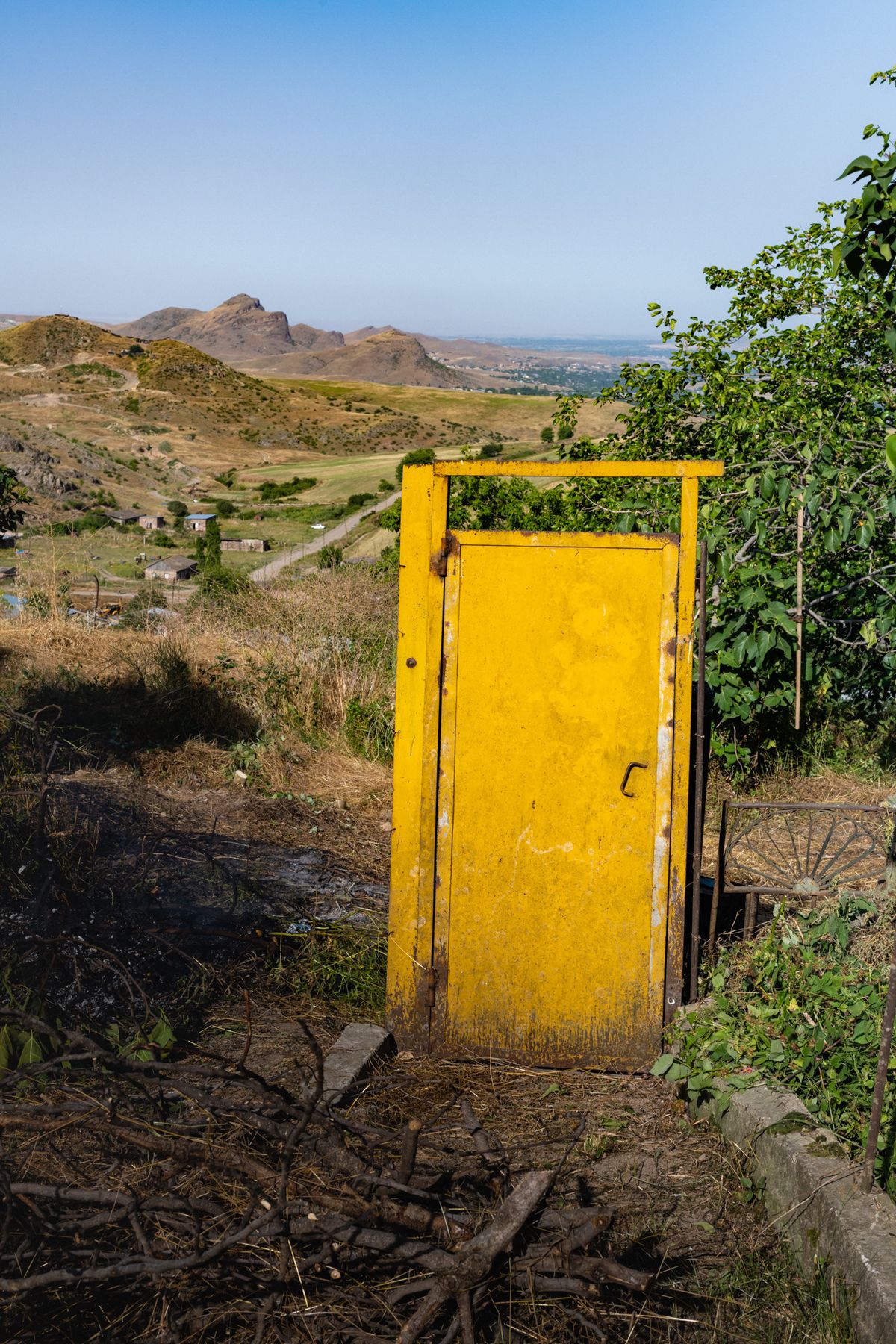 A yellow door in its frame, seen close, rocks behind