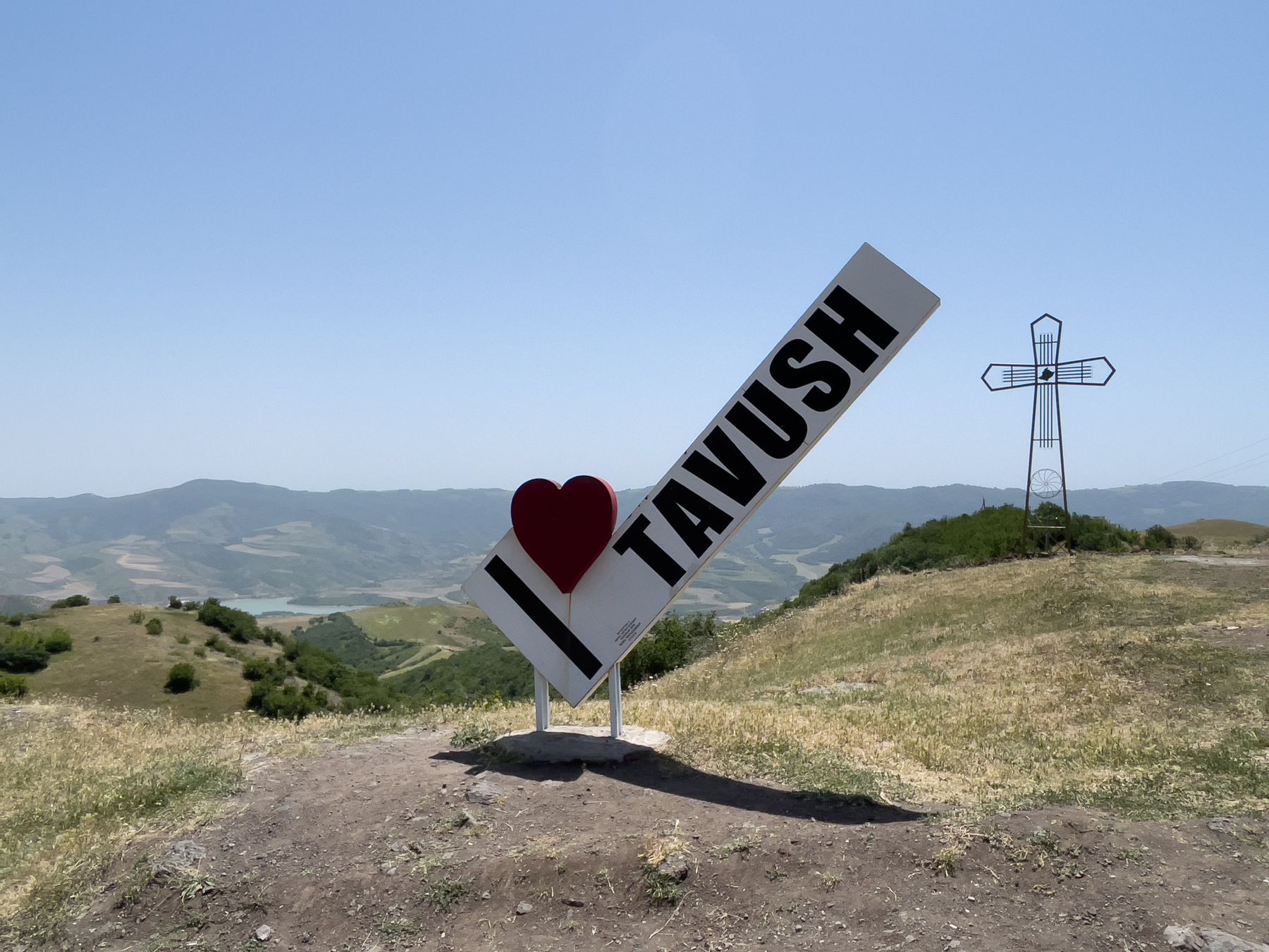 A large I love Tavush sign on a hilltop under a blue sky